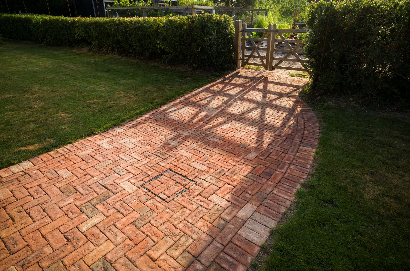 Herringbone brick path laid through clipped hedges